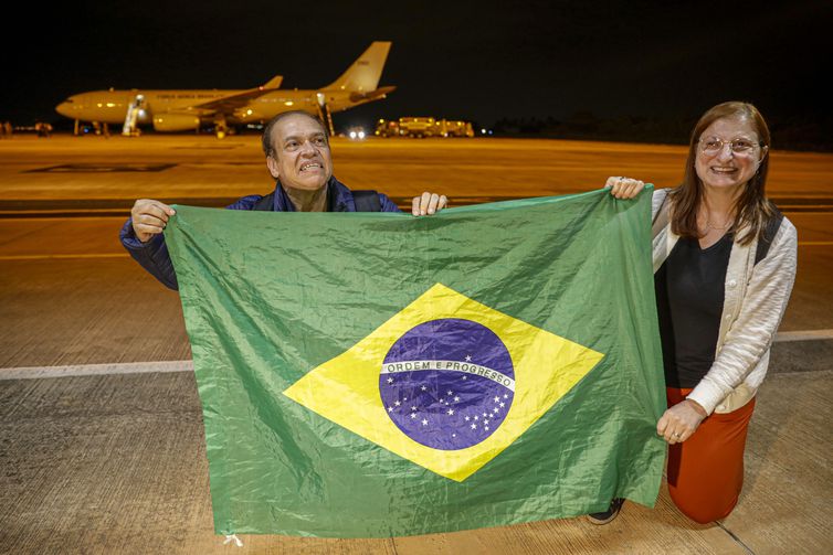 Casal segura bandeira do Brasil ao desembarcar de primeiro voo de resgate da FAB